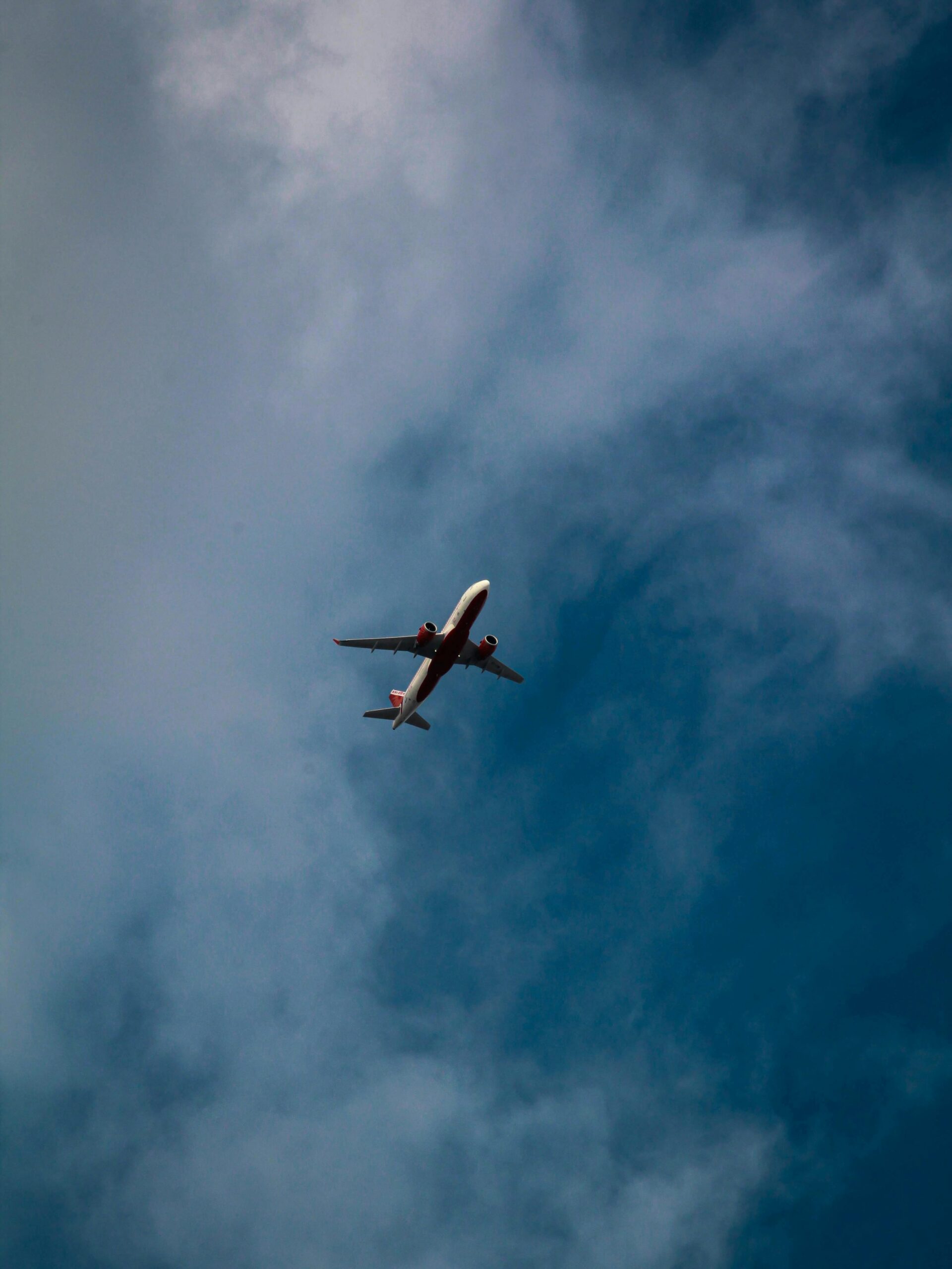 A low angle view of a commercial airplane flying against a backdrop of blue sky and white clouds.